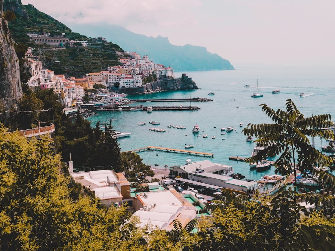 A picturesque Mediterranean coastal village built into dramatic cliffs with colorful architecture, fishing boats, and turquoise waters—a typical scene from Italy's Amalfi Coast. - Photo by silvia trigo on Unsplash
